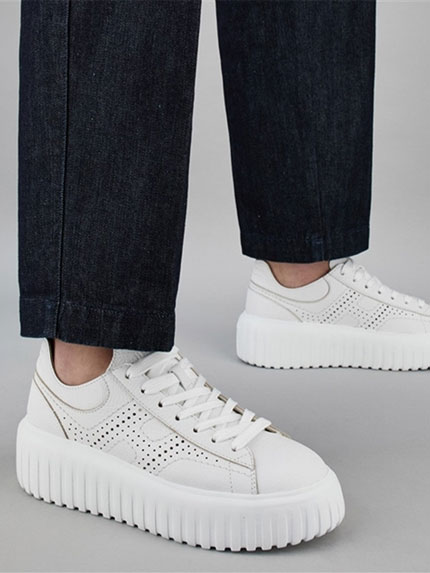 Paire de baskets blanches portées par une femme en jean