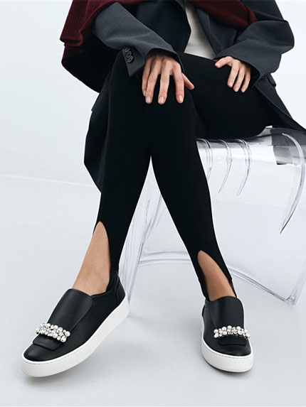 Paire de chaussures noires avec des starss portées par une femme assise sur une chaise transparente